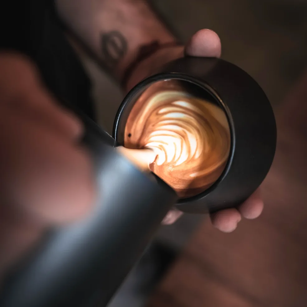 Barista vertiendo la leche para dibujar el latte art